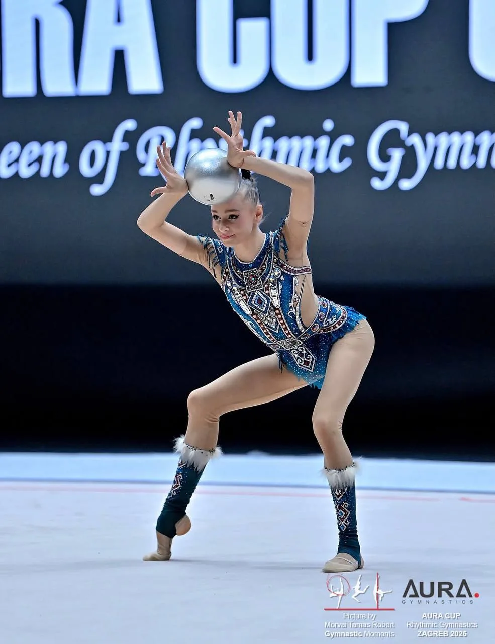 Гимнастка в соревновательном купальнике выполняет упражнение с мячом на Aura Cup 2026